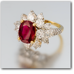 Pala International - Thai ruby surrounded by diamonds in a gold ring setting.